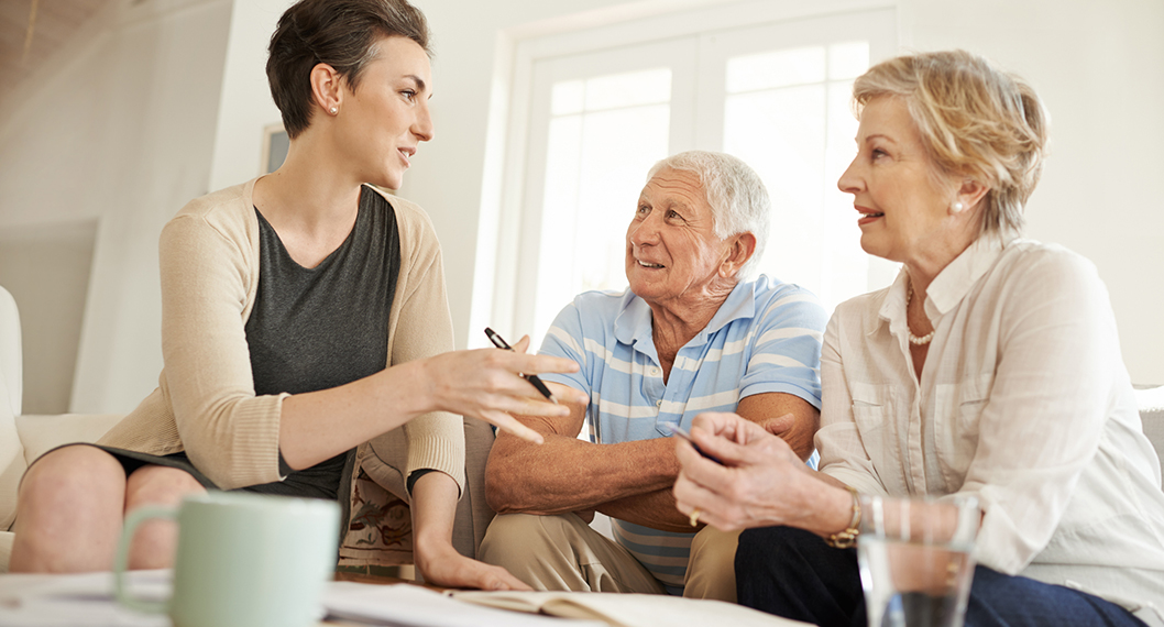 Young woman explaining the difference between Medicare Advantage vs Original Medicare to a Medicare eligible couple 